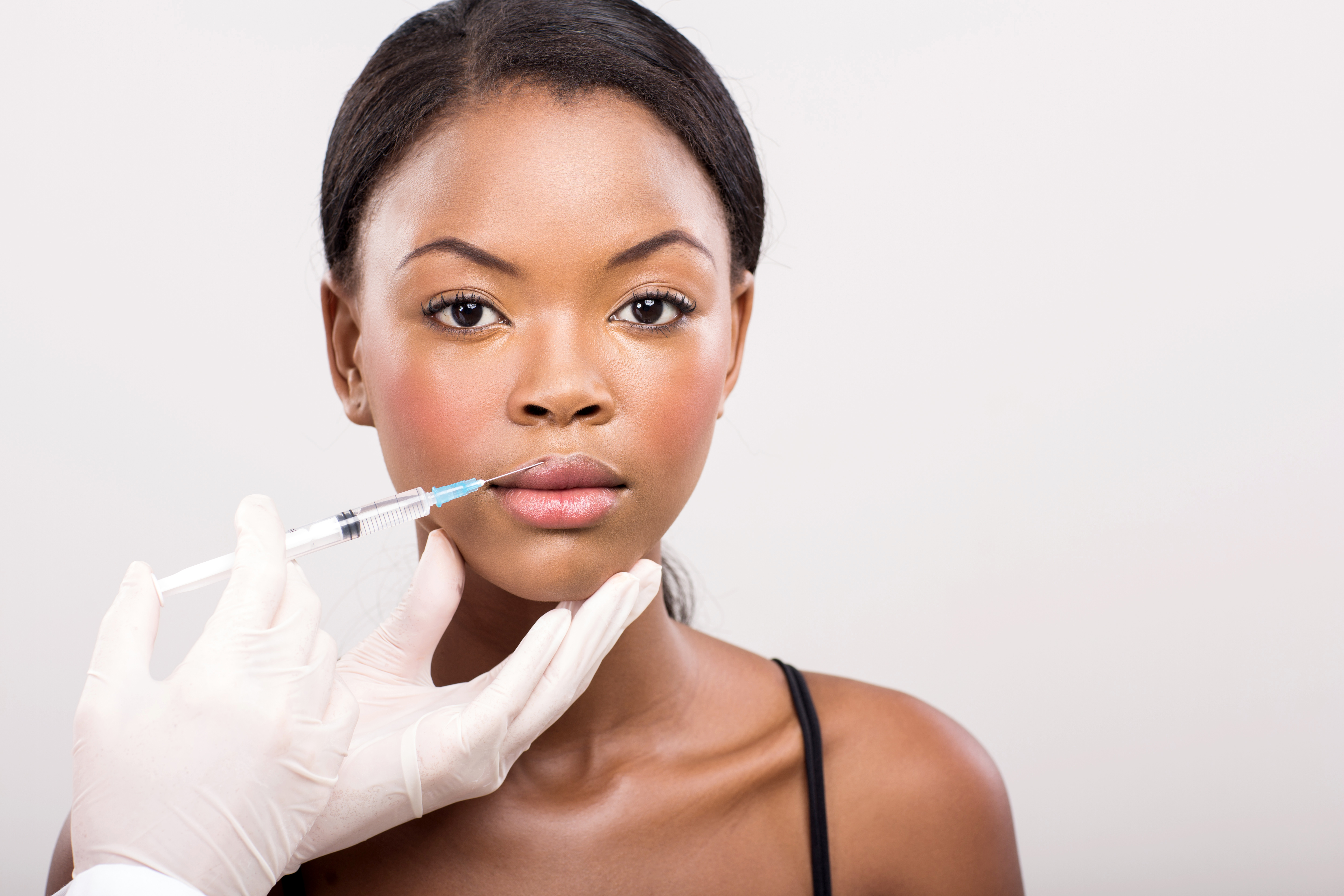 pretty african girl receiving cosmetic injection on her lips